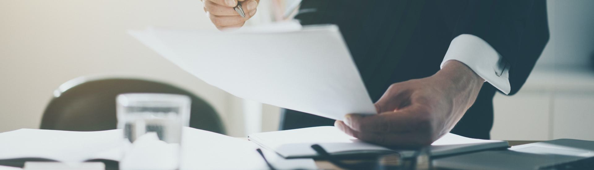 Professional standing over desk looking at contract.